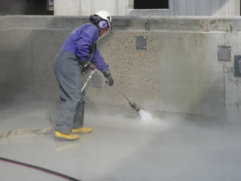 Operative using high-pressure water jetting equipment to prepare a concrete tank wall